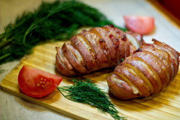 Potato accordion. Garnish potatoes stuffed with bacon and herbs on a wooden stand.