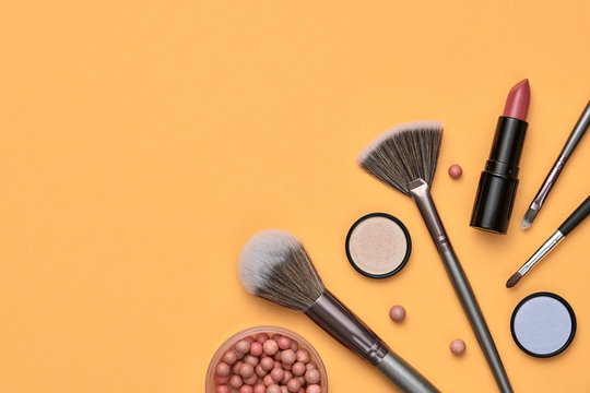 Fashion cosmetic makeup autumn Set. Minimal. Beauty product on orange background. Trendy accessories Brushes Eyeshadow art fashionable Flat lay. Creative make up fall autumnal concept