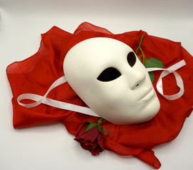 Theater or romance concept. Closeup of white classical theatrical mask and red rose as a symbol of sexual freedom.