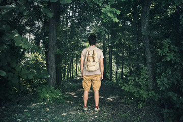 Man standing in front of a wild nature. Lonely male person in a mysterious dark forest