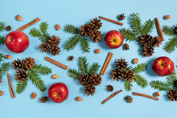 Christmas or winter composition. Frame made of fir tree branches, pine, acorn, red apple and cinnamon on pastel blue background. Christmas, winter, new year concept. Flat lay, top view, copy space