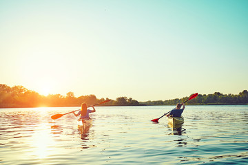 People kayak during sunset in the background. Have fun in your free time.