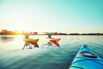 People kayak during sunset in the background. Have fun in your free time.