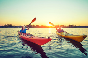 People kayak during sunset in the background. Have fun in your free time. - obrazy, fototapety, plakaty