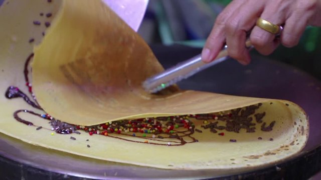Making of crepes pancakes in open Thailand street market.crepes with chocolate sauce and chopped nuts for a tasty dessert