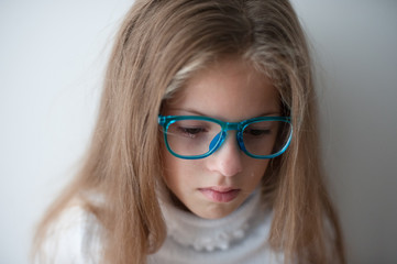 Fototapeta na wymiar state of mind concept of beautiful caucasian little girl in blue glasses crying with bitter tear in eye being sad and frustrated