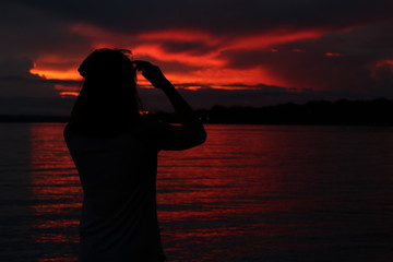 Fototapeta premium silhouette of woman with perfume bottle of water at sunset