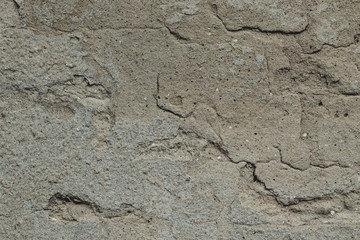 Old ruined and cracked wall made of red bricks with remains of plaster. 