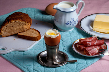 Soft-boiled egg on a silver breakfast stand. Bacon, butter