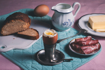 Soft-boiled egg on a silver breakfast stand. Bacon, butter