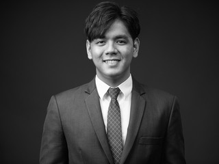Young handsome Asian businessman smiling portrait shot in black and white
