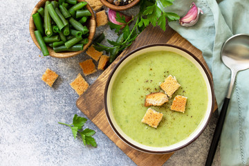 Vegetarian dish. Dietary delicious cream soup of green beans on a light background. Top view flat lay. Free space for your text.