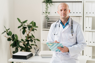 Serious and confident doctor with clipboard and pen making prescriptions