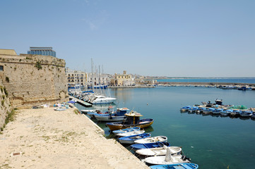 Fototapeta na wymiar Fishing boats tied up to piers in the Old City near the castle. Gallipoli, Province of Lecce, Apulia, Italy