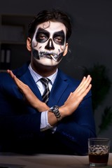 The businessman with scary face mask working late in office