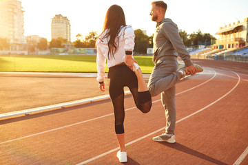 Couple in sportswear doing warm-up at the stadium