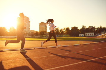 Young man and woman runners run in the morning at dawn.