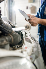Digital tablet held by mature master of contemporary technical repair service