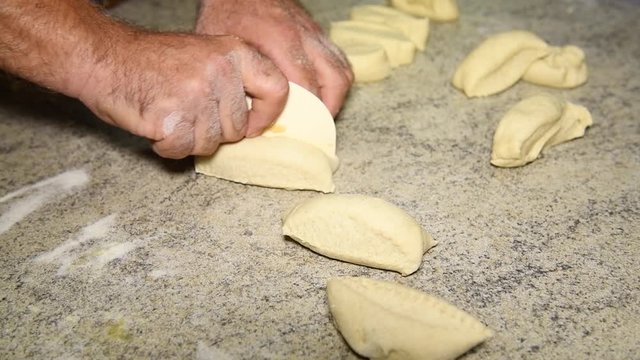 male hands cut dough into pieces to make Italian panzerotti pies on a table. Cooking Panzerotti in Puglia, Salento, Italy