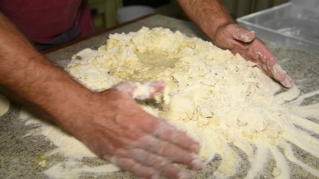 A man prepares to knead the dough for panzerotti or pies: a man kneads dough: in the video, male hands collect flour to make a lump of dough. Durum wheat flour, Senatore Cappelli