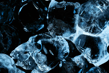 frozen transparent ice cubes with blue lighting isolated on black