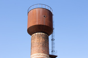 Concrete water tank on the tower: large outdoor public water storage tanks for water supply in villages or communities in the city. On the sky background with copy space.