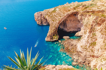 Blue Grotto in Malta. Pleasure boat with tourists runs. Natural arch window in rock