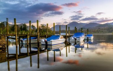 Derwentwater moored boats at sunset with reflections on the water. located in the Lake District national park Cumbria.