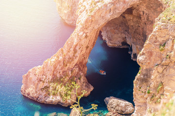 Blue Grotto in Malta. Pleasure boat with tourists runs. Natural arch window in rock