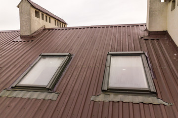 Roof of a house made from metal sheets with attic windows.