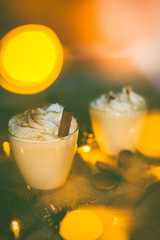 Eggnog in glasses with whipped cream and cinnamon on wooden table for Christmas and winter holidays. Copyspace included.