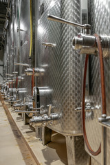 A line of stainless steel vats used to make wine in a cellar of a winery