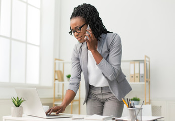 Afro Lady Talking On Cellphone Typing On Laptop In Office