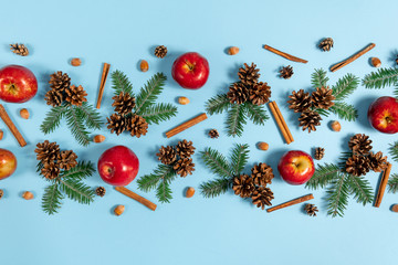 Christmas composition. Tree branches, pine, red apple, acorn and cinnamon on pastel blue...