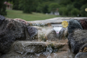 Glass of martini cocktail at swimming pool with ocean and palm tree background. A glass of blue martini cocktail welcome drink bar.Selective focus. season and holidays concept.