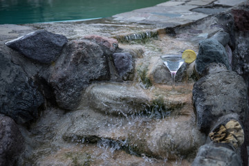 Glass of martini cocktail at swimming pool with ocean and palm tree background. A glass of blue martini cocktail welcome drink bar.Selective focus. season and holidays concept.