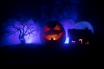 Horror view of Halloween pumpkin with scary smiling face. Head jack lantern with spooky building