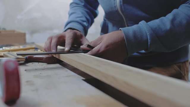 a carpenter takes measurements of a wooden board using a square and marks the measurements with a pencil. 4k. 4k video. slow motion. 24 fps
