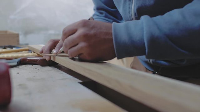 a carpenter measures a wooden board with a square at an angle and marks the dimensions with a pencil. 4k. 4k video. slow motion. 24 fps