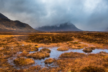 Buachaille Etive Mor shrouded in clouds with marshy water and grass in the foreground. Glencoe, Scotland