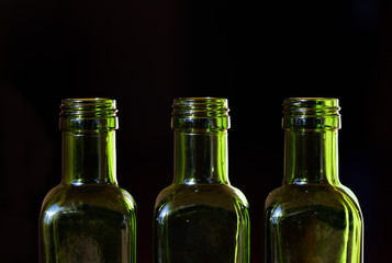 three empty green glass bottles standing against dark background with text box
