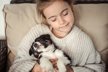 A little girl holding a puppy in her hands .