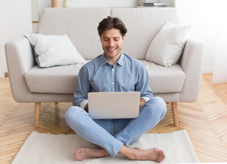 Successful Freelancer Working On Laptop Sitting On Floor At Home