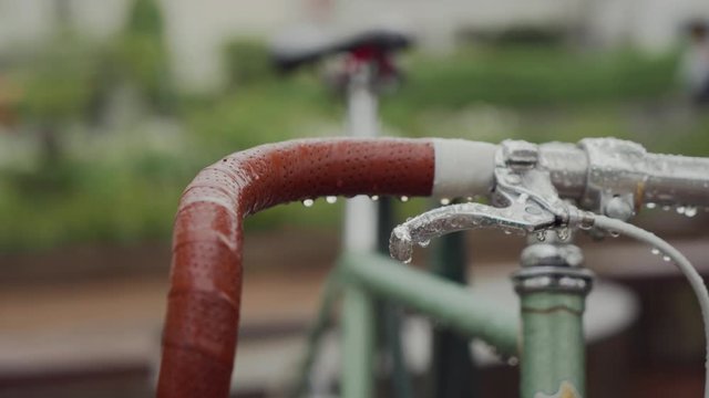 Wet handlebars with brown handles on a rainy day. Close up