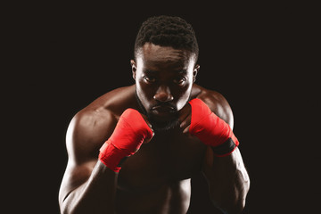 Professional fighter in boxing stance posing over black studio background
