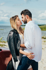 attractive woman and handsome man hugging and kissing outside