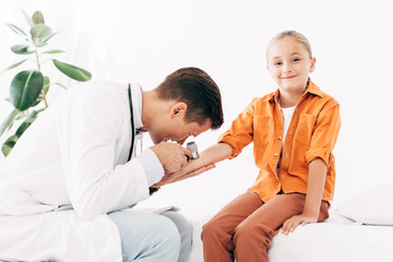 focused pediatrist in white coat examining child with dermascope