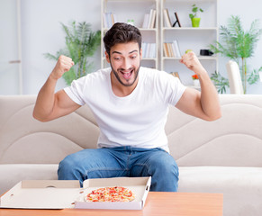 Man eating pizza having a takeaway at home relaxing resting