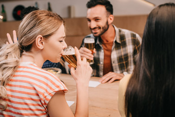 young woman gesturing while drinking light beer with closed eyes