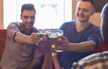 Happy mates clinking glasses with beer together